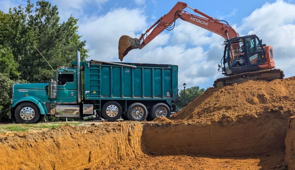 Excavation contractor using an excavator to load soil into a dump truck in Southern Maryland